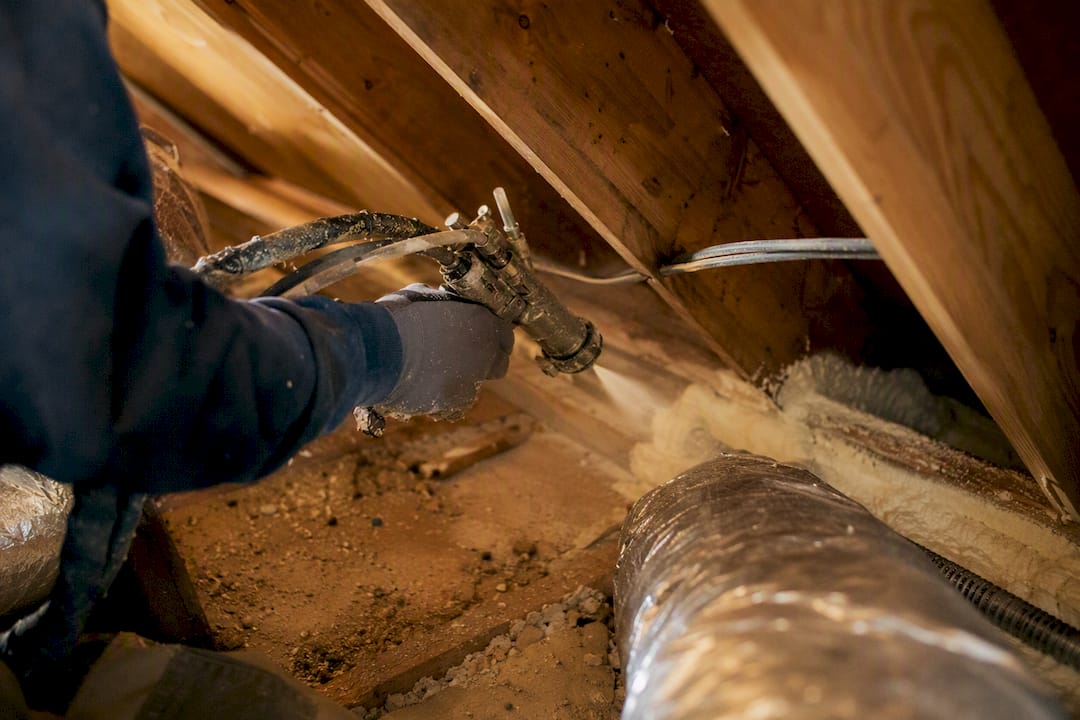 Applying spray foam to attic gaps for air sealing