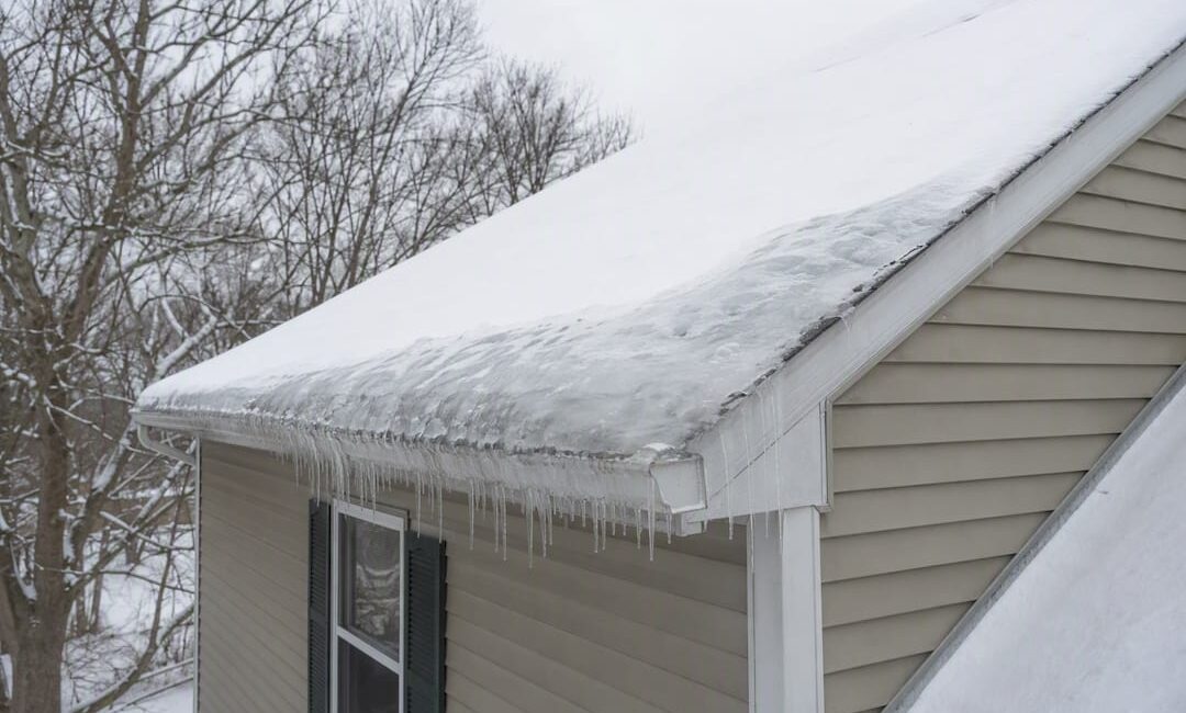 Ice dam forming on shingled roof eaves in winter