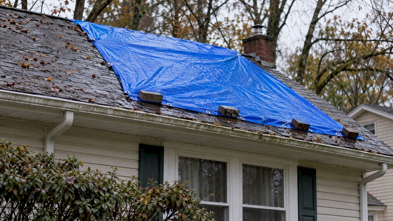 Blue tarp covering storm-damaged roof