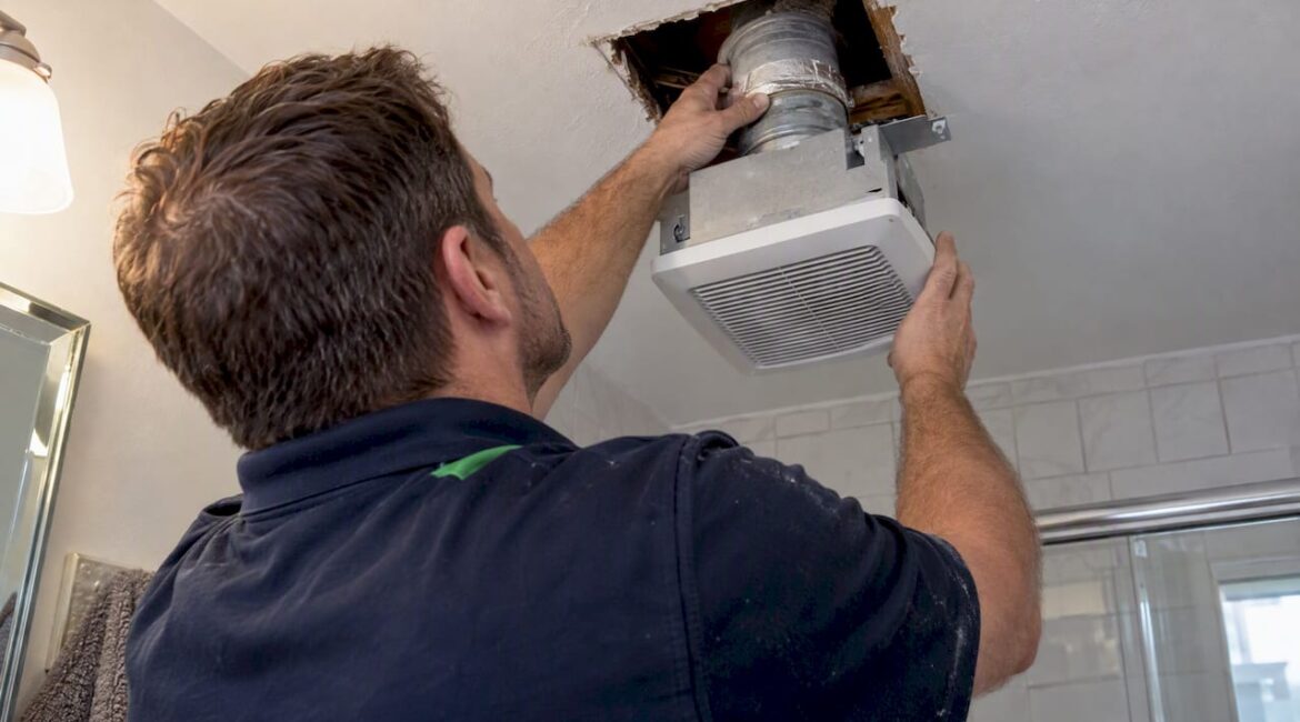 Technician inspecting bathroom exhaust fan duct